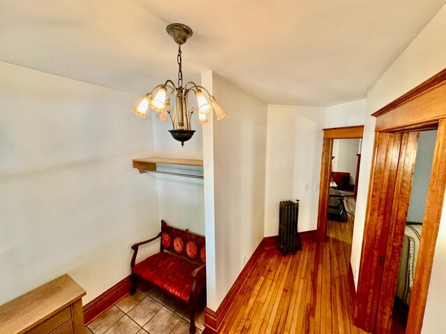 corridor with an inviting chandelier, radiator, and baseboards