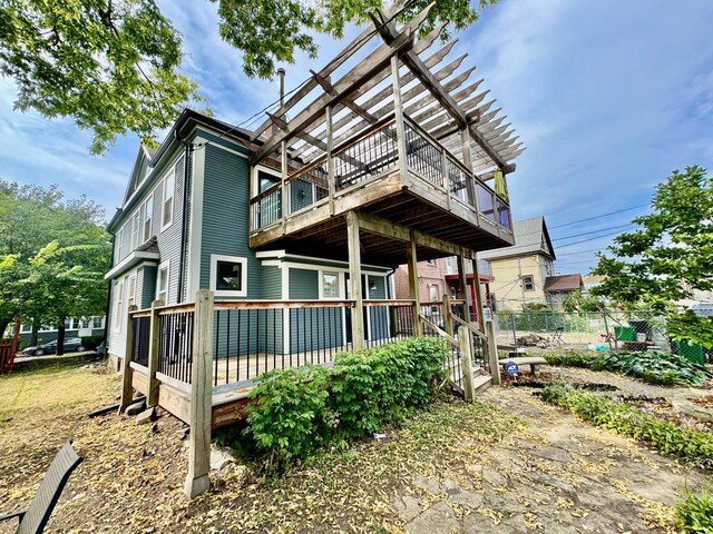 rear view of house with a wooden deck, a pergola, and fence