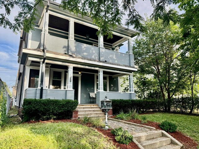 view of front facade with covered porch, a balcony, and a front lawn