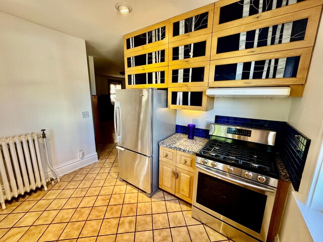 kitchen featuring appliances with stainless steel finishes, radiator, recessed lighting, light tile patterned floors, and under cabinet range hood