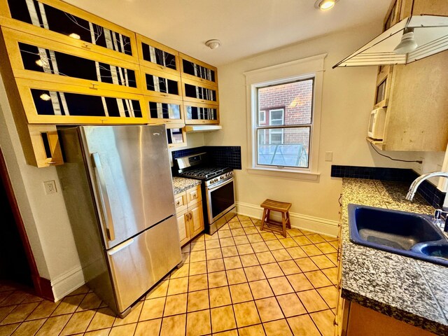 kitchen featuring a sink, baseboards, light tile patterned floors, and stainless steel appliances