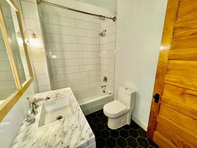 bathroom featuring shower / bathtub combination, toilet, tile patterned floors, and a sink