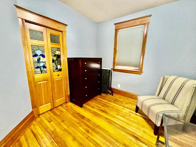 sitting room with radiator, baseboards, and light wood finished floors