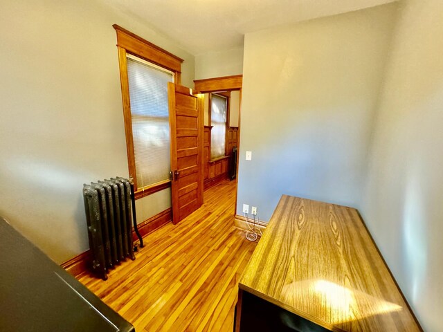 interior space with baseboards, radiator, and wood finished floors