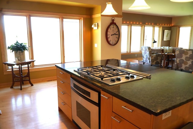 kitchen featuring stainless steel appliances, dark countertops, light wood finished floors, and open floor plan