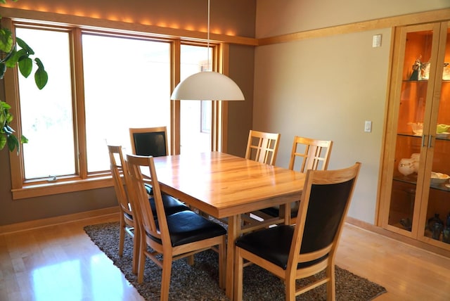 dining space featuring light wood-type flooring and baseboards