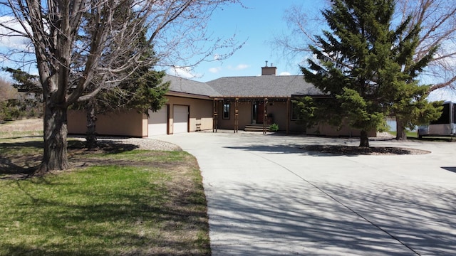 ranch-style home with driveway, stucco siding, a garage, and a chimney
