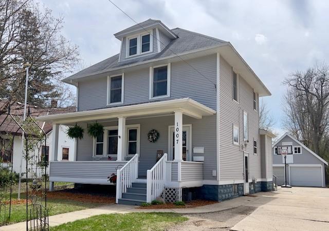 traditional style home featuring a garage, an outbuilding, and a porch