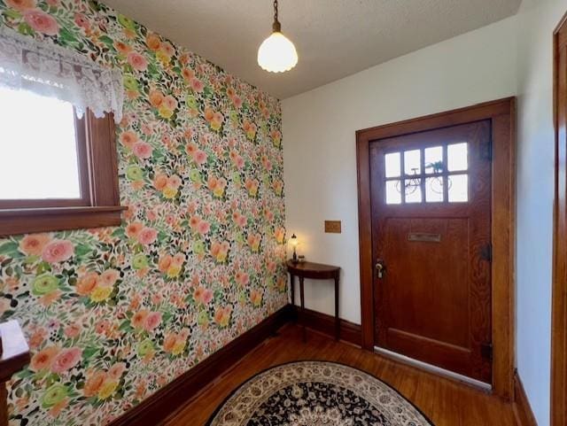 entrance foyer with baseboards, wood finished floors, and wallpapered walls