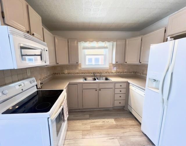 kitchen featuring light wood-type flooring, a sink, white appliances, and tasteful backsplash
