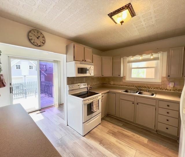 kitchen with decorative backsplash, white appliances, an ornate ceiling, a sink, and light wood finished floors