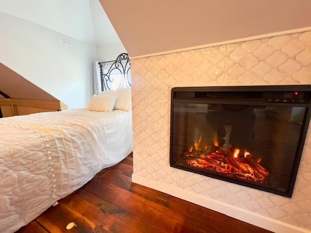 bedroom with baseboards, lofted ceiling, and dark wood-type flooring