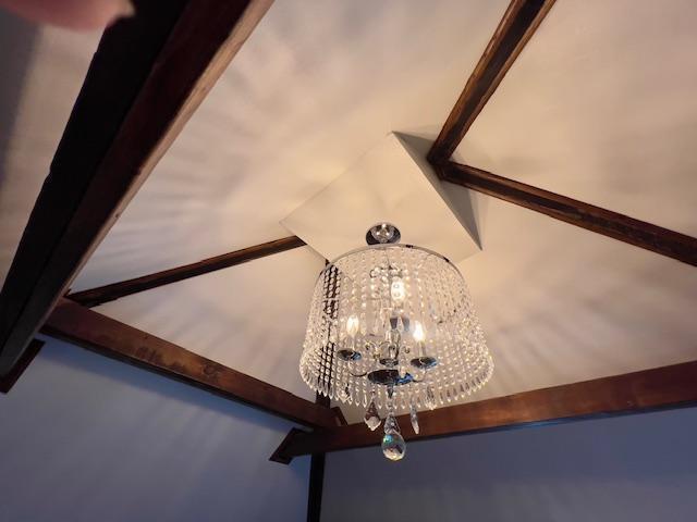 room details with beamed ceiling and a notable chandelier