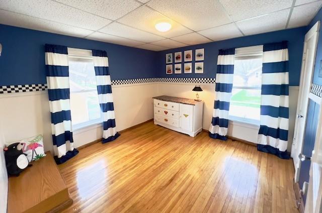 interior space featuring wood finished floors, baseboards, and a drop ceiling