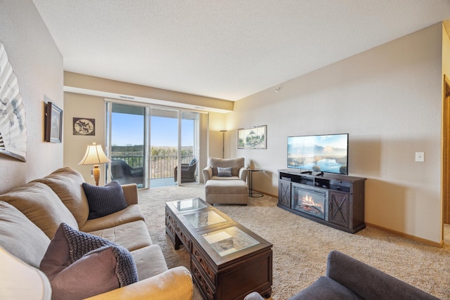 living area featuring baseboards, carpet flooring, and a glass covered fireplace