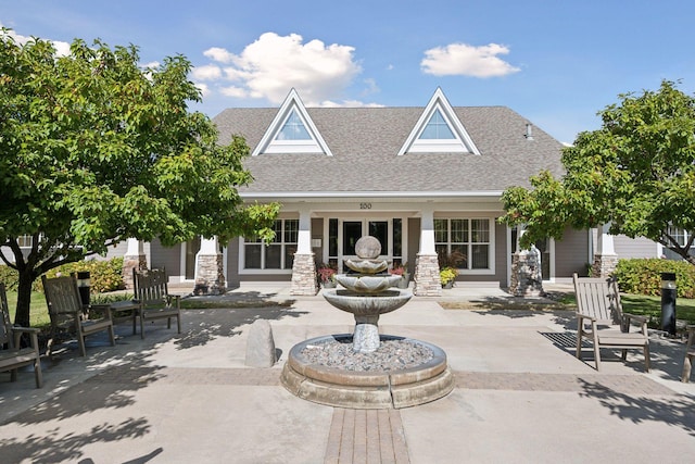 back of house with a patio area, a shingled roof, and stone siding