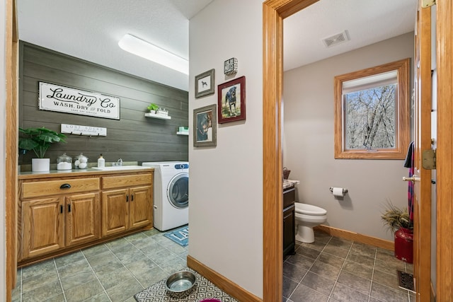 laundry area with washer / clothes dryer, visible vents, cabinet space, baseboards, and wooden walls