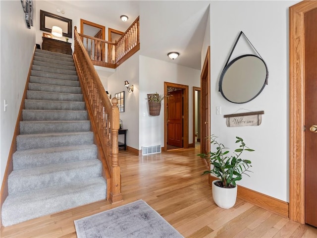 foyer with baseboards, visible vents, stairs, and light wood finished floors