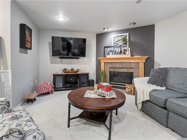 living room featuring a tile fireplace and carpet flooring