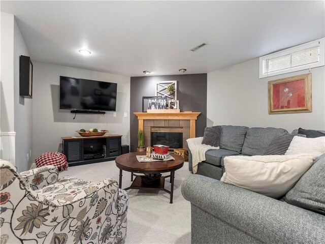 living area featuring a tiled fireplace, visible vents, and light colored carpet