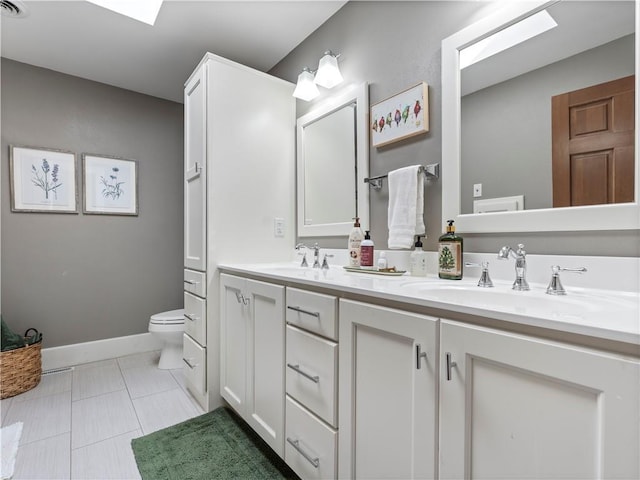 bathroom with toilet, double vanity, a sink, and tile patterned floors