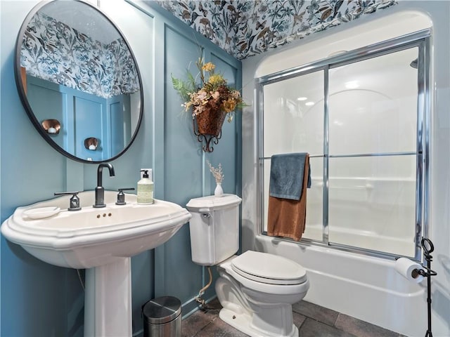 bathroom featuring enclosed tub / shower combo, toilet, and baseboards
