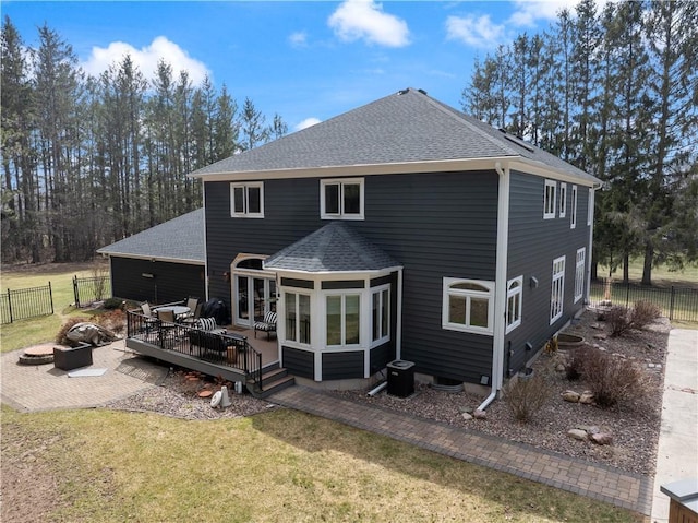 rear view of house with an outdoor fire pit, a wooden deck, a yard, and roof with shingles