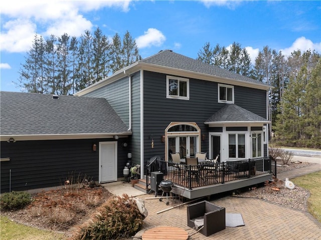 back of house with a deck, a patio area, french doors, and a shingled roof