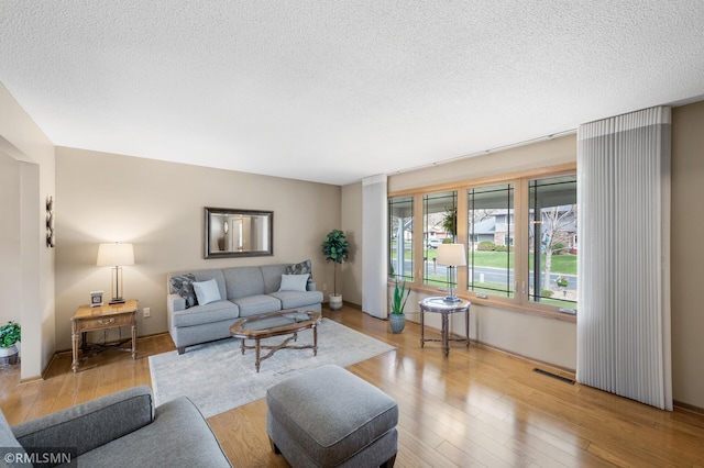 living area with a textured ceiling, visible vents, and wood finished floors