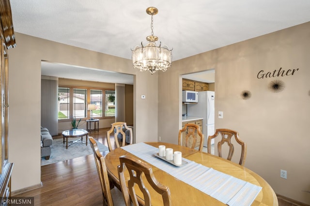 dining area with an inviting chandelier and dark wood-type flooring