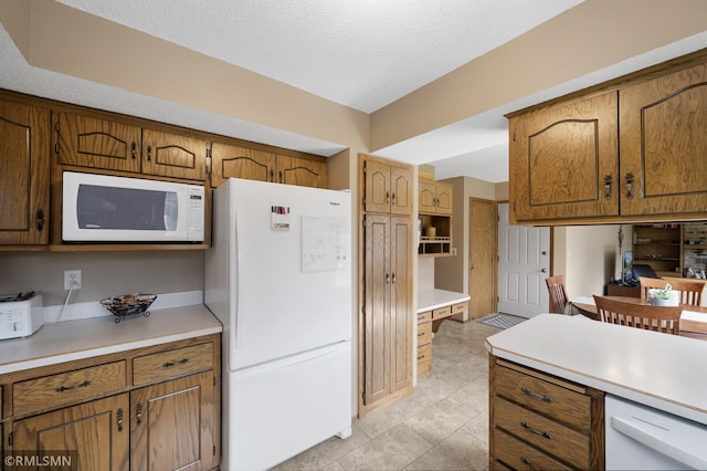 kitchen featuring brown cabinetry, white appliances, and light countertops