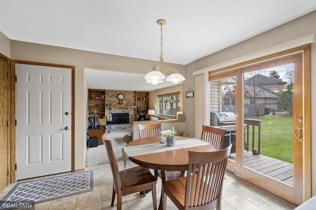 dining area with light tile patterned floors, built in shelves, a chandelier, and a fireplace