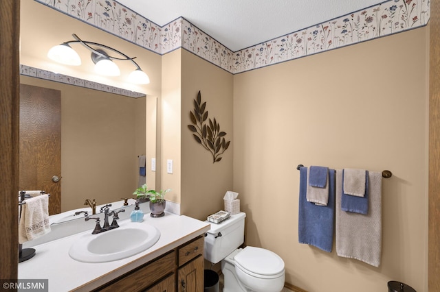 bathroom with a textured ceiling, vanity, and toilet