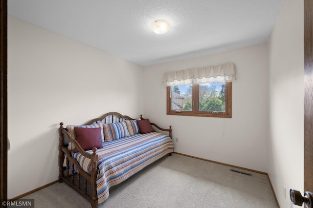 bedroom featuring carpet flooring, a textured ceiling, visible vents, and baseboards