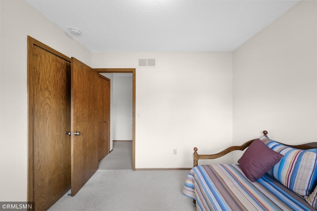 bedroom with a textured ceiling, visible vents, and carpet