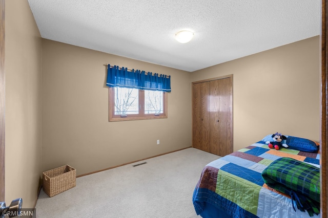 bedroom featuring carpet floors, a closet, baseboards, visible vents, and a textured ceiling