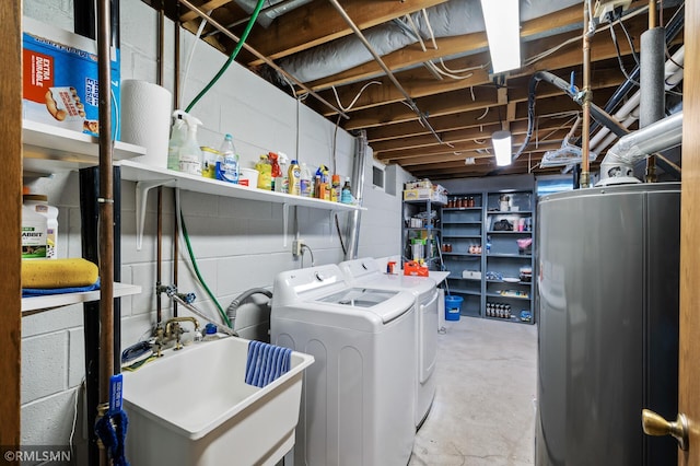 washroom with a sink, concrete block wall, washing machine and dryer, laundry area, and water heater