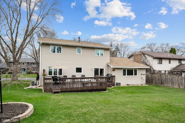 back of house with a lawn, fence, a shingled roof, and a wooden deck