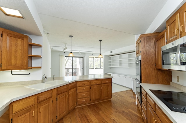 kitchen featuring a sink, appliances with stainless steel finishes, open shelves, wood finished floors, and brown cabinets