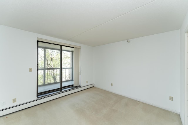 spare room with a baseboard heating unit and light colored carpet