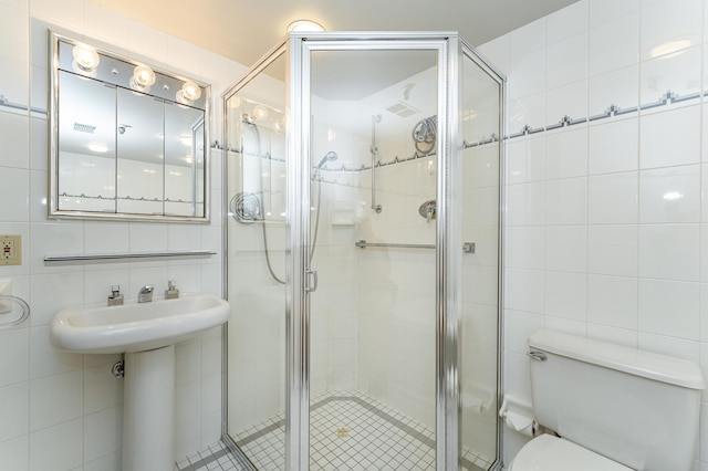 bathroom with tile walls, a shower stall, and toilet