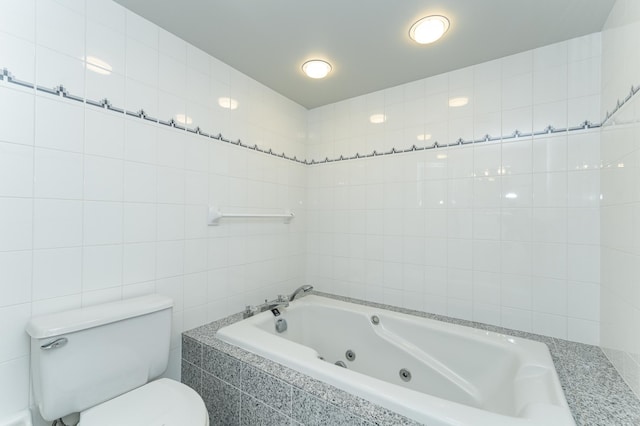 bathroom with a whirlpool tub, toilet, and tile walls