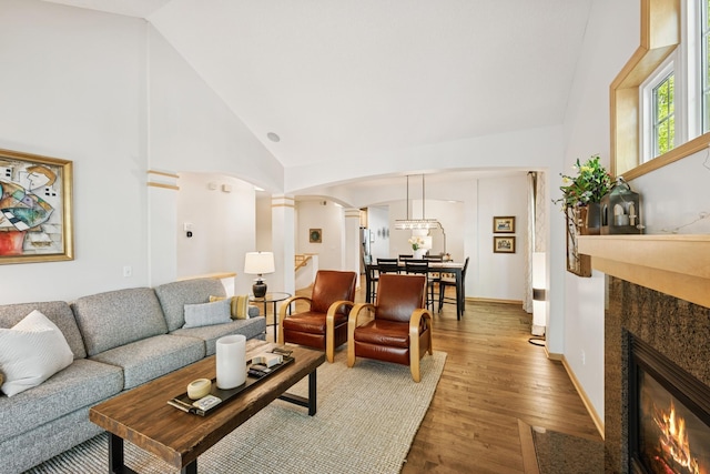 17300 Tilia Rdg, Eden Prairie, MN 55347 - living room with arched walkways, light wood-style floors, decorative columns, a tiled fireplace, and high vaulted ceiling