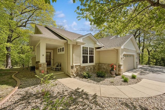 17300 Tilia Rdg, Eden Prairie, MN 55347 - view of front of home with roof with shingles, stone siding, an attached garage, concrete driveway, and central AC unit