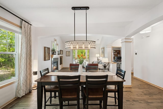 17300 Tilia Rdg, Eden Prairie, MN 55347 - dining room featuring dark wood-style flooring, a chandelier, a glass covered fireplace, and decorative columns