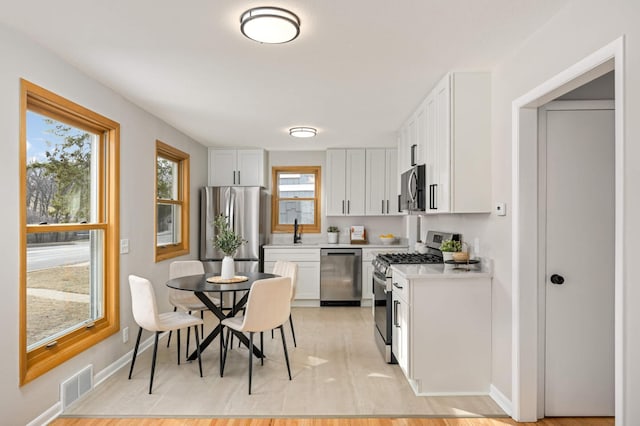 4836 Bloomington Ave, Minneapolis, MN 55417 - kitchen featuring appliances with stainless steel finishes, light countertops, a sink, and white cabinets