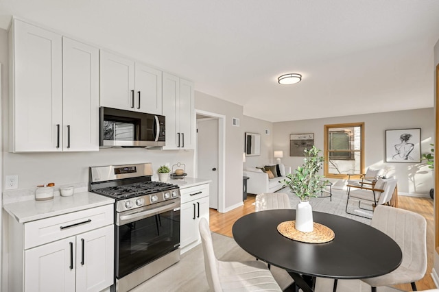 4836 Bloomington Ave, Minneapolis, MN 55417 - kitchen with stainless steel range with gas cooktop, light countertops, white cabinets, and open floor plan