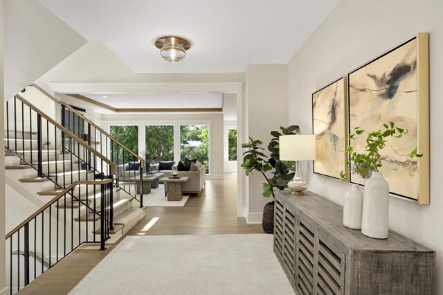 entryway with a raised ceiling, wood finished floors, baseboards, and stairs