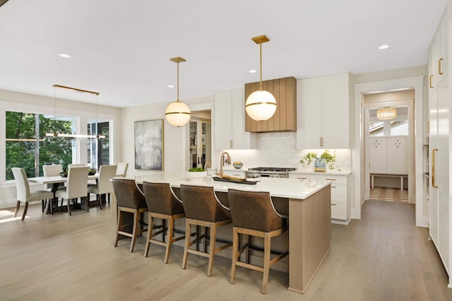 kitchen with light countertops, a sink, backsplash, and light wood-style floors