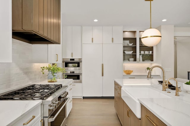 kitchen with light wood-type flooring, stainless steel appliances, decorative backsplash, and a sink